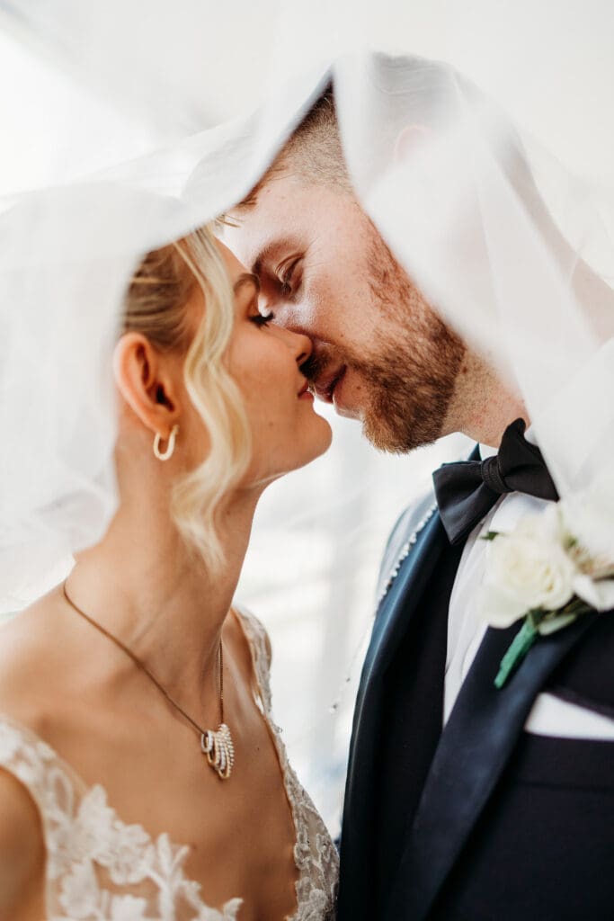 Bride and groom share a kiss under the brides veil