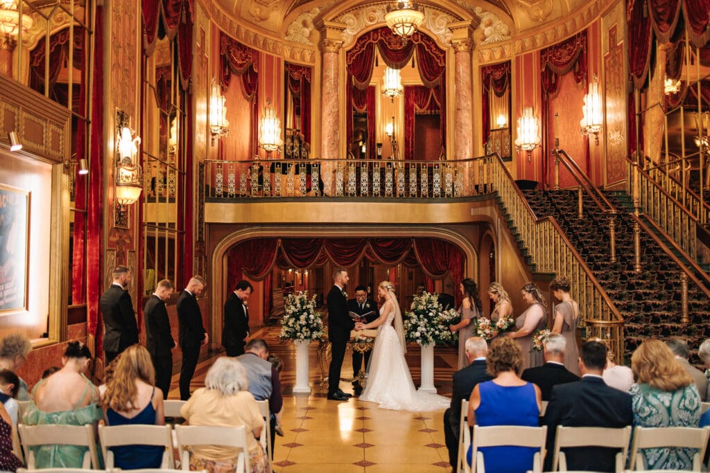 Bride and groom standing together during their wedding ceremony at the Warner theater in Erie, PA